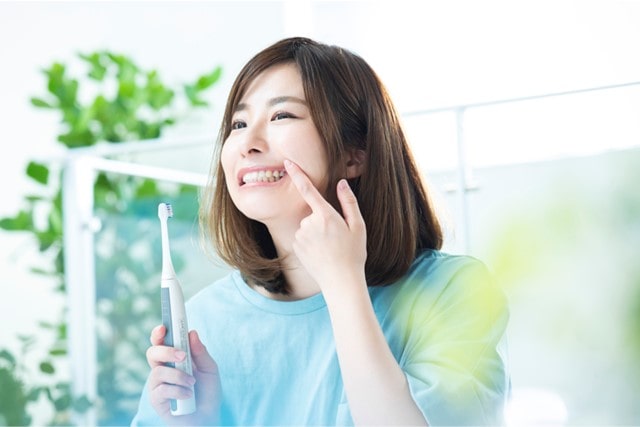 電動歯ブラシでブラッシングしている女性